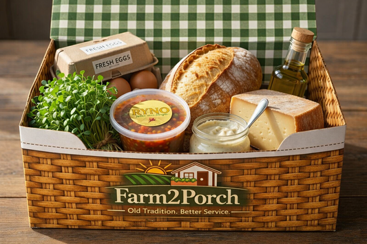 Farm2Porch food basket with bread, cheese, and other items on a wooden table.